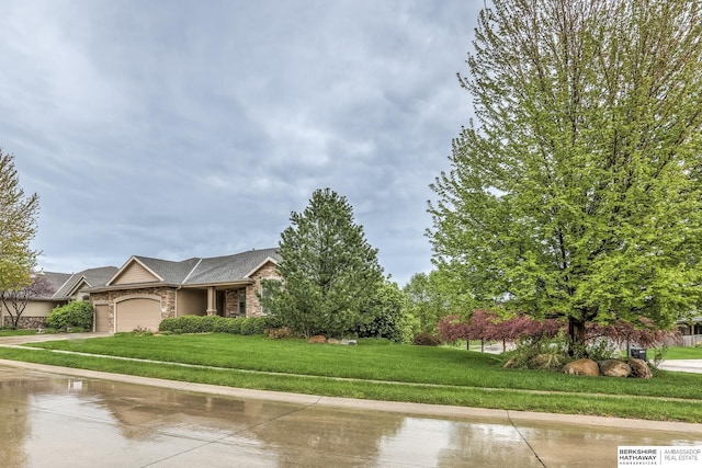 view of front of house featuring a front lawn, stone siding, brick siding, an attached garage, and driveway
