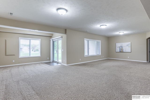 unfurnished room featuring carpet floors, a textured ceiling, baseboards, and visible vents