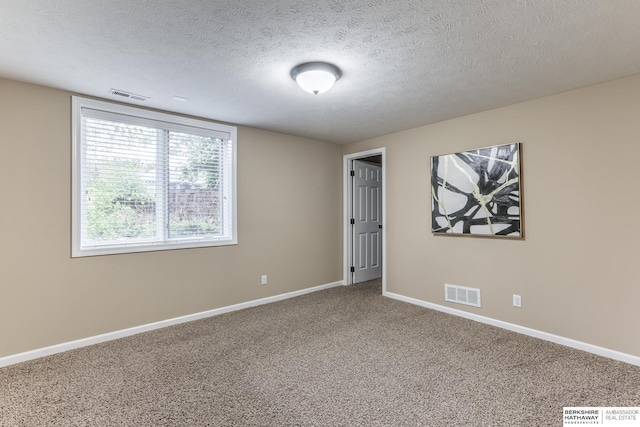 carpeted spare room featuring baseboards, a textured ceiling, and visible vents