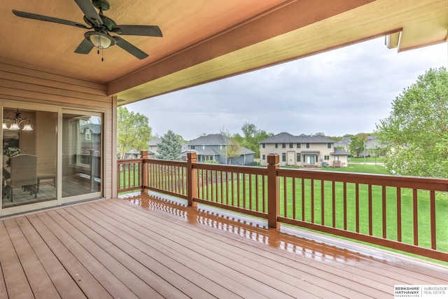 wooden deck with a ceiling fan, a yard, and a residential view