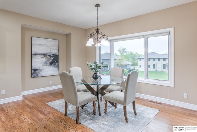 dining room with baseboards, visible vents, light wood-style flooring, and a chandelier
