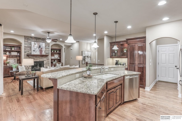 kitchen with a fireplace, stainless steel dishwasher, light wood-type flooring, and a sink
