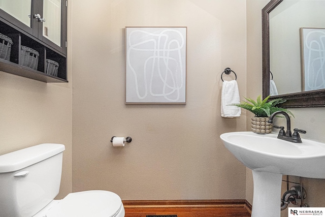 half bath featuring toilet, baseboards, and wood finished floors
