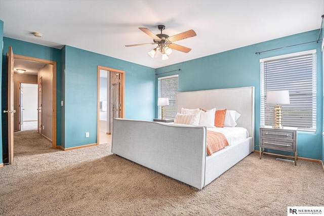 carpeted bedroom with baseboards, ceiling fan, and ensuite bath