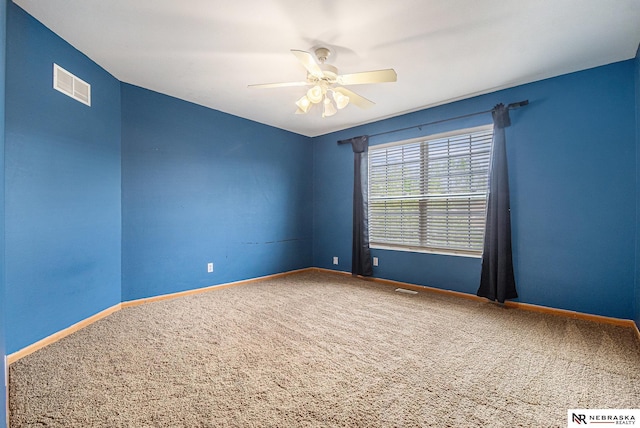 carpeted spare room featuring visible vents, baseboards, and ceiling fan