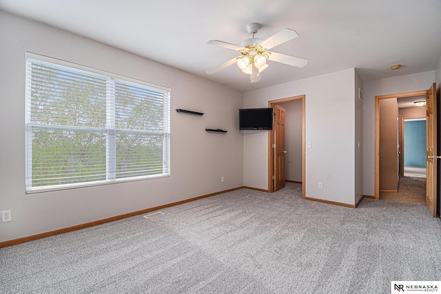 unfurnished bedroom featuring baseboards, ceiling fan, light carpet, and a walk in closet