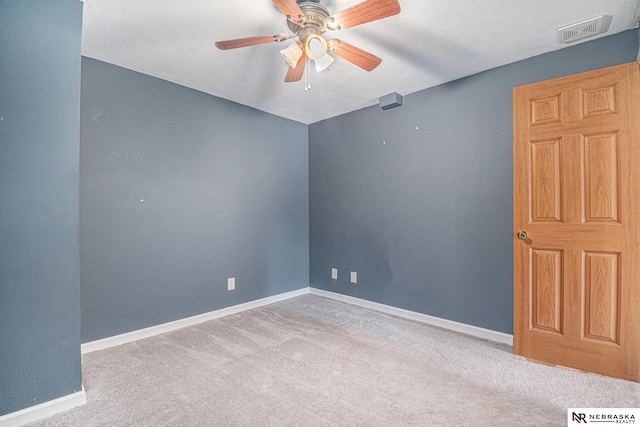 carpeted empty room with ceiling fan, visible vents, and baseboards