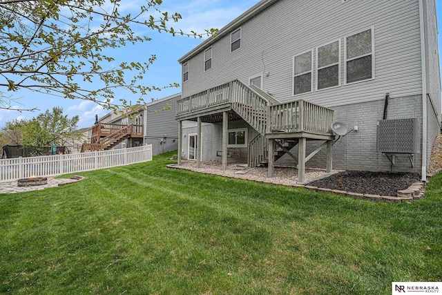 back of house featuring a deck, stairway, a fenced backyard, an outdoor fire pit, and a yard