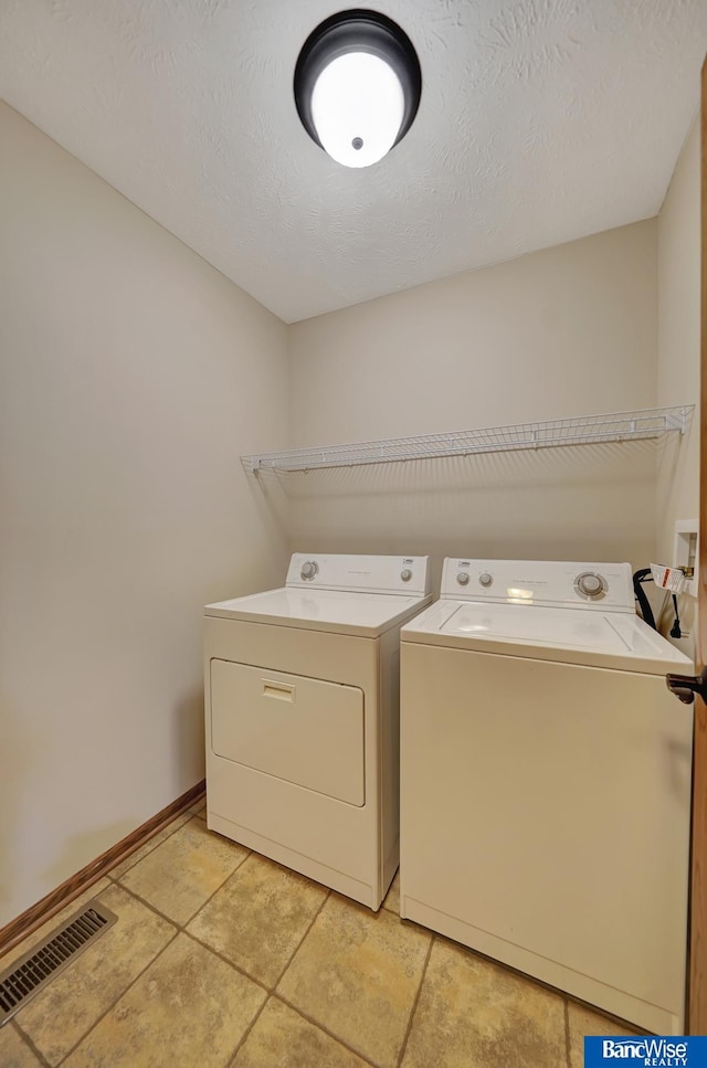 laundry area with independent washer and dryer, light tile patterned flooring, laundry area, visible vents, and baseboards