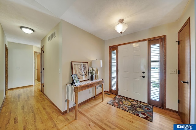 entrance foyer with visible vents, light wood-style flooring, and baseboards
