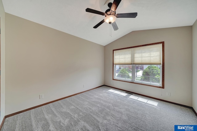 empty room with lofted ceiling, carpet, ceiling fan, and baseboards