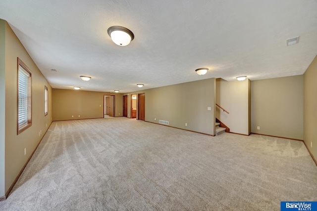 unfurnished room with stairway, light carpet, and baseboards