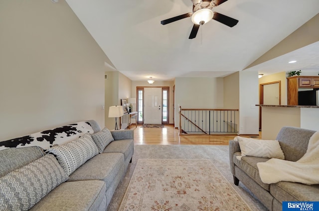 living room with a ceiling fan, visible vents, light wood-style flooring, and lofted ceiling