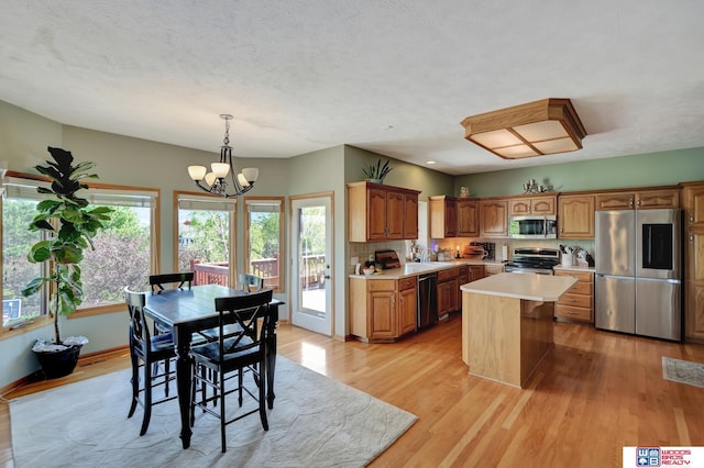 kitchen with stainless steel appliances, light countertops, a chandelier, light wood-type flooring, and plenty of natural light