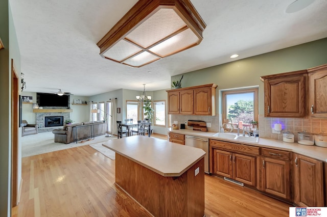 kitchen with stainless steel dishwasher, a fireplace, a sink, light countertops, and recessed lighting