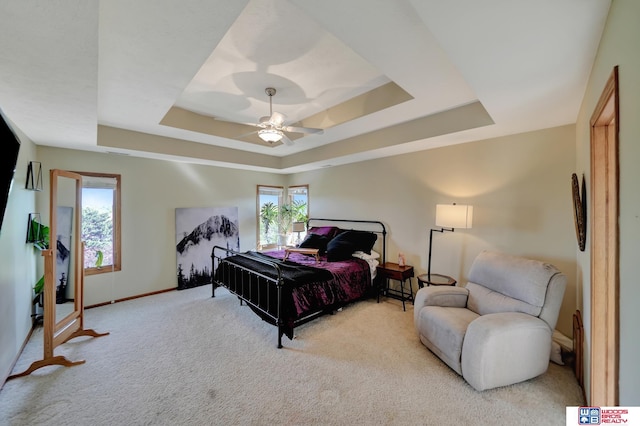 carpeted bedroom with a tray ceiling, baseboards, and a ceiling fan