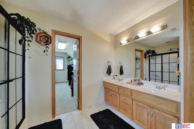 bathroom with double vanity, marble look tile flooring, and a shower