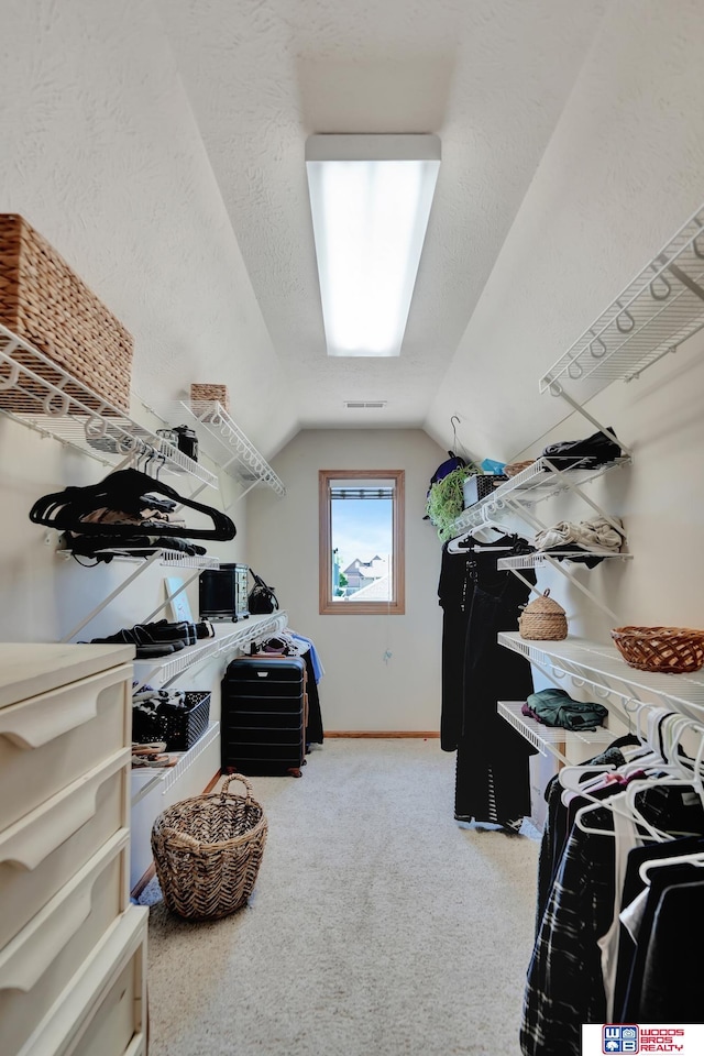 spacious closet with lofted ceiling and carpet flooring
