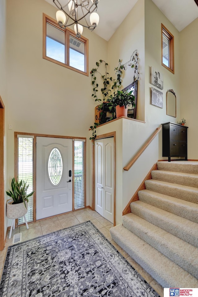 tiled foyer entrance with a chandelier, stairs, and a high ceiling