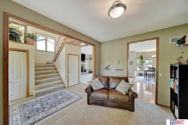 carpeted living room with stairway and plenty of natural light