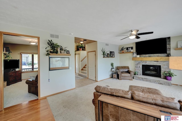 living room with light wood-type flooring, a ceiling fan, stairway, a fireplace, and baseboards