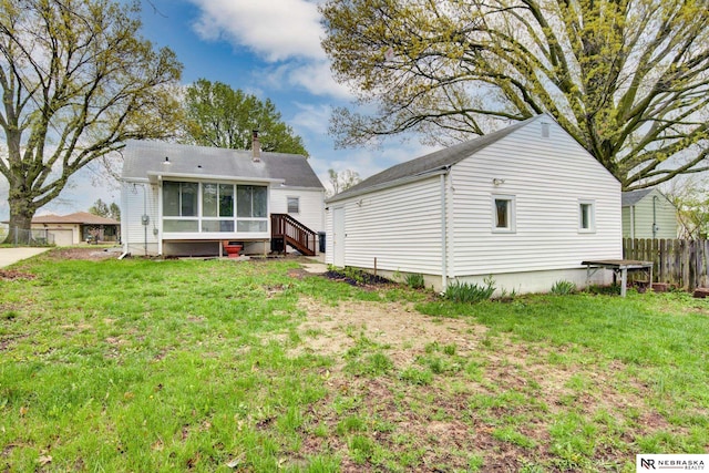 back of property with a sunroom, fence, and a yard