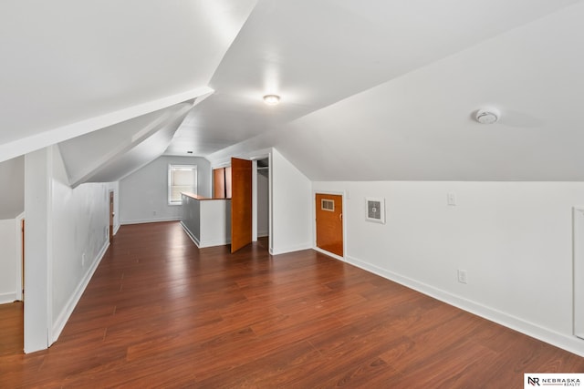 additional living space featuring baseboards, visible vents, vaulted ceiling, and dark wood-type flooring