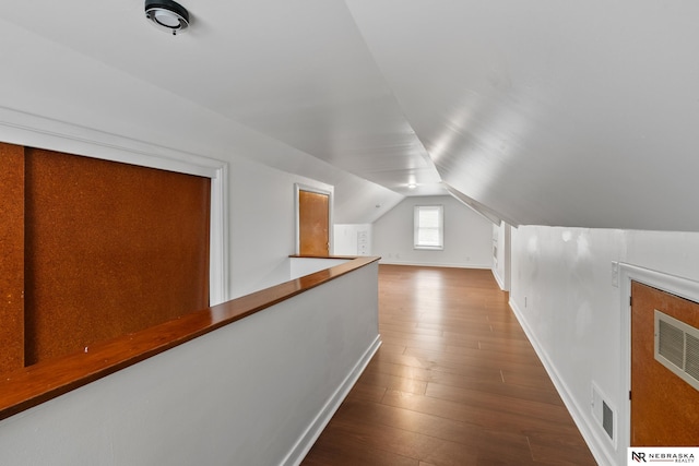 bonus room with baseboards, lofted ceiling, hardwood / wood-style floors, and visible vents