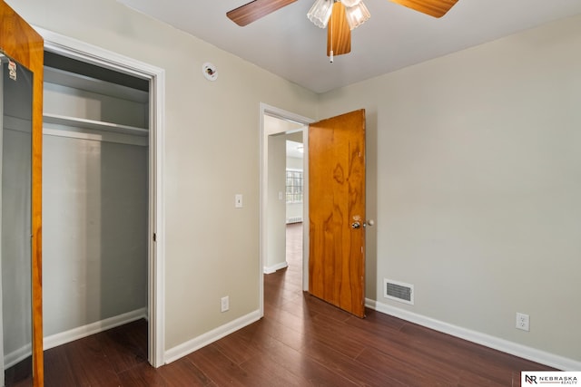unfurnished bedroom with baseboards, a closet, wood finished floors, and visible vents