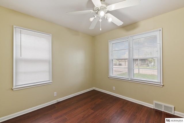 spare room featuring baseboards, visible vents, dark wood-style floors, and ceiling fan