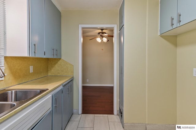 kitchen with ceiling fan, backsplash, a sink, light tile patterned floors, and baseboards