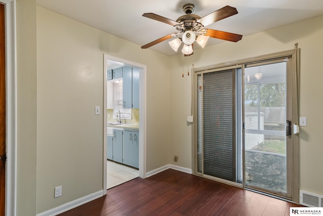 interior space with a ceiling fan, visible vents, wood finished floors, a sink, and baseboards