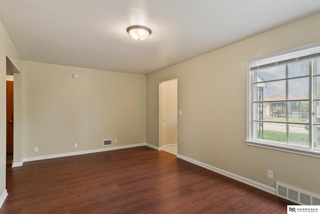 unfurnished room with visible vents, baseboards, and dark wood-type flooring