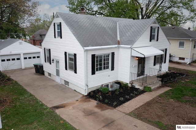 view of front facade with a chimney, a shingled roof, an outdoor structure, and a garage