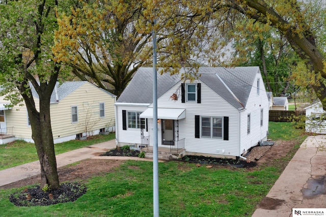 bungalow-style home featuring a front lawn, roof with shingles, and fence