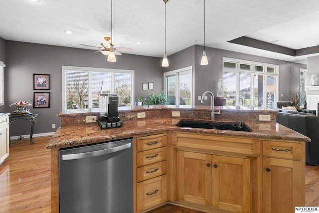 kitchen with dishwasher, stone countertops, a sink, light wood-type flooring, and open floor plan