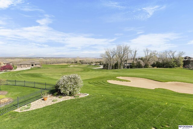 view of community with golf course view, a lawn, and fence
