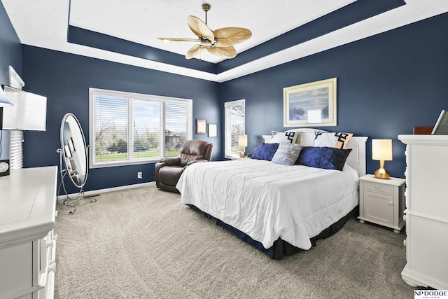 bedroom with baseboards, a ceiling fan, a tray ceiling, and dark carpet