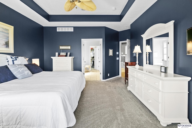 carpeted bedroom featuring baseboards, a ceiling fan, visible vents, and a raised ceiling