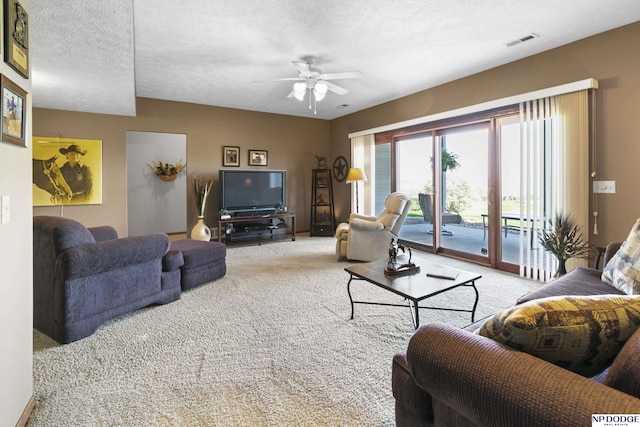 living room with a textured ceiling, carpet, visible vents, and ceiling fan