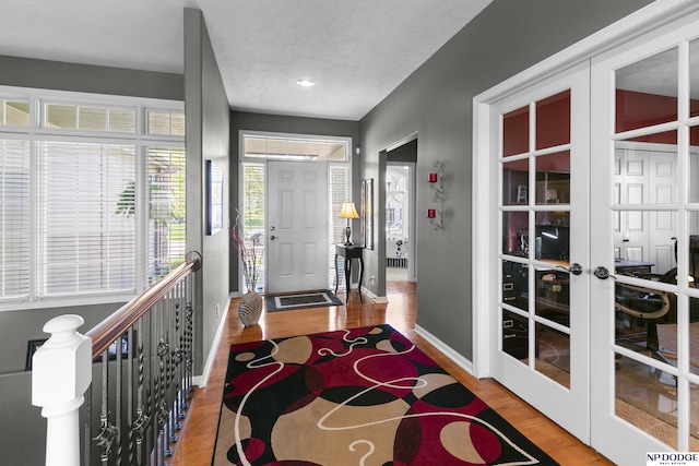 foyer entrance with wood finished floors, baseboards, and french doors