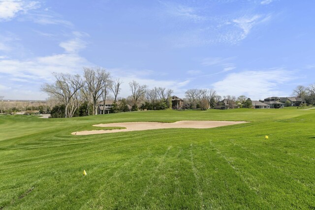 view of property's community with view of golf course and a lawn