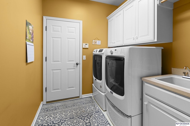 washroom featuring washing machine and clothes dryer, baseboards, a sink, and cabinet space