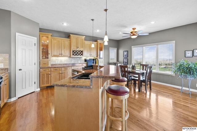 kitchen with baseboards, a sink, a breakfast bar, and light wood-type flooring