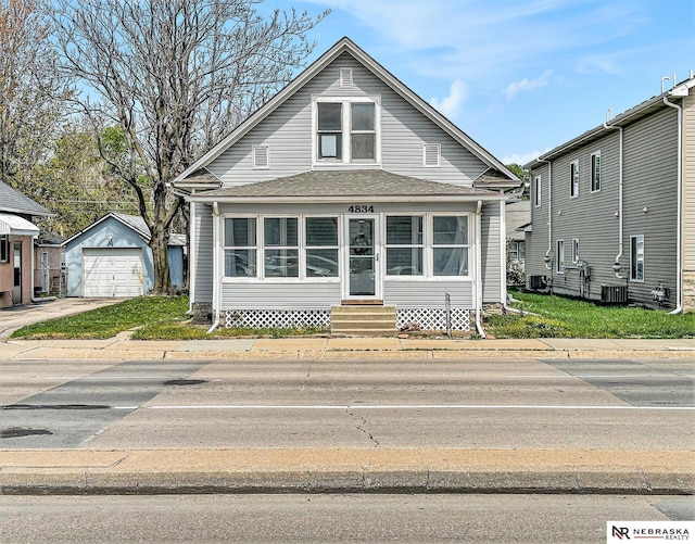 bungalow-style home featuring driveway, entry steps, an outbuilding, central air condition unit, and a garage