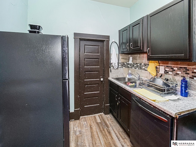 kitchen with tasteful backsplash, light wood-style flooring, a sink, light countertops, and black appliances