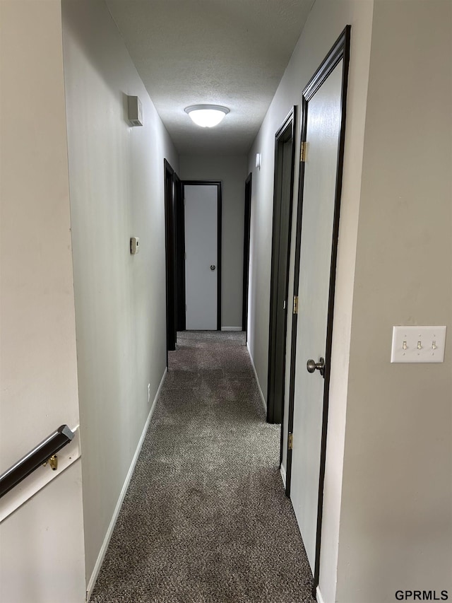hall featuring carpet floors, a textured ceiling, and baseboards