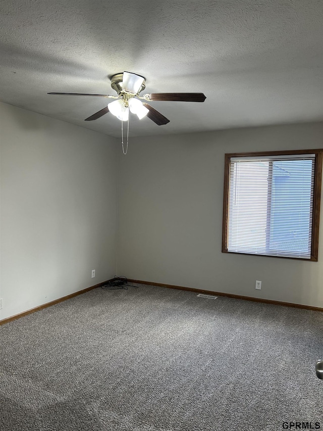 carpeted spare room with a ceiling fan, baseboards, and a textured ceiling
