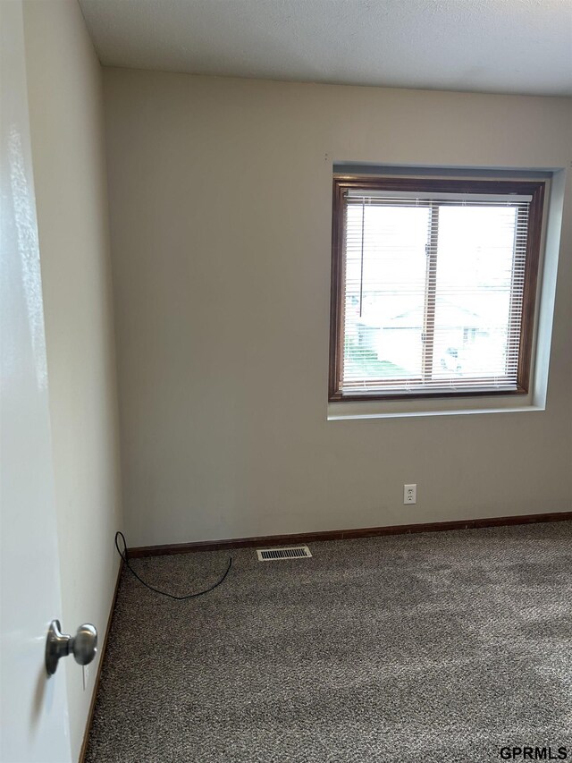 carpeted spare room with visible vents and baseboards