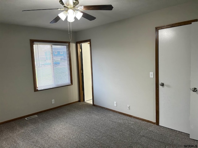 carpeted empty room with visible vents, a ceiling fan, and baseboards